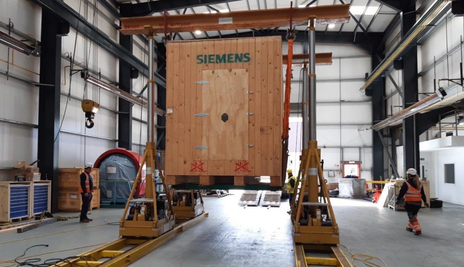 Crated industrial equipment being lifted inside a factory hall