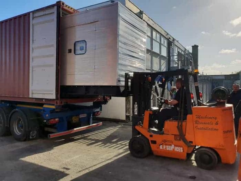 Forklift loading a wrapped machine into a shipping container
