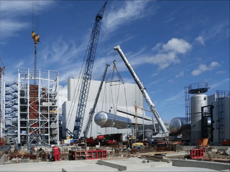 Cranes lifting a process vessel during industrial plant construction